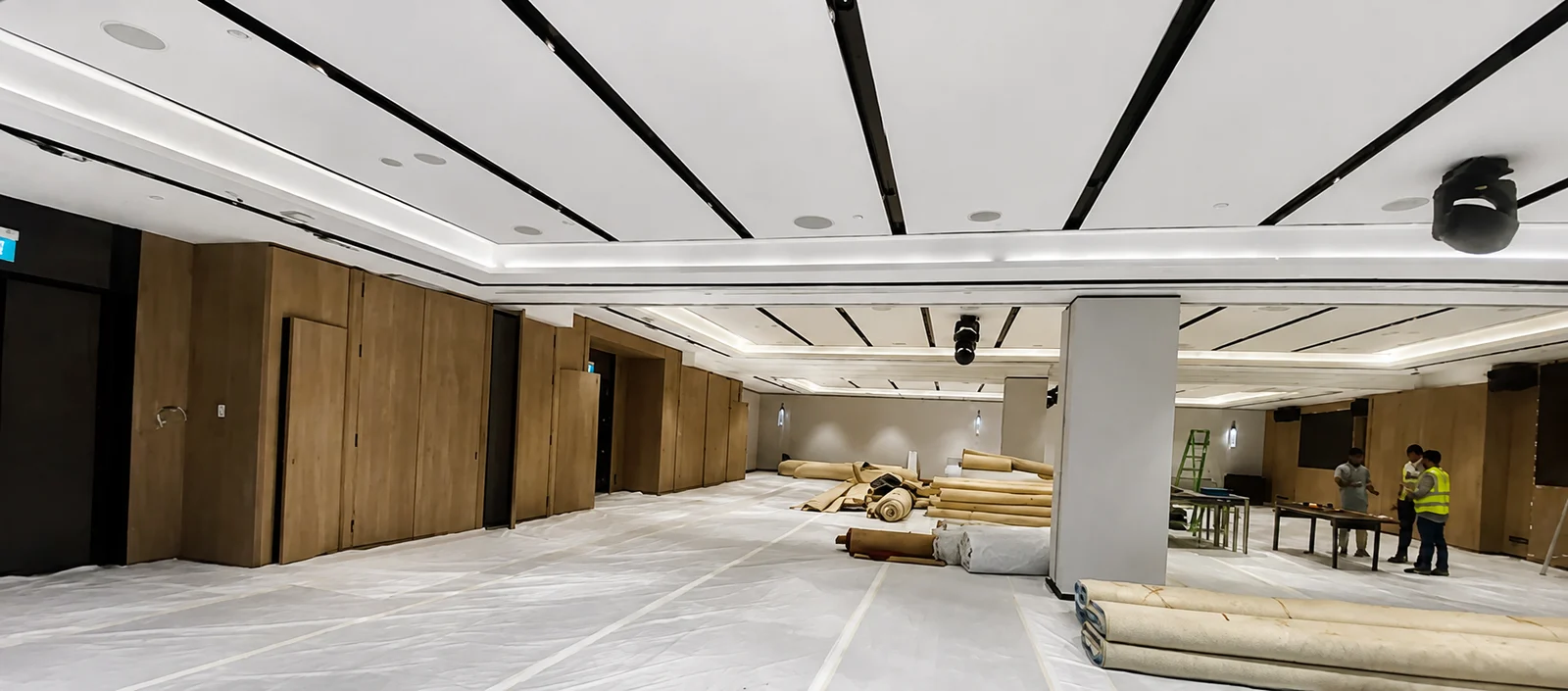 Hospitality interior during fit-out, with floor protection and ceiling works